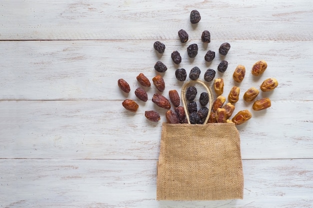 Photo different varieties of dates fruits are laid out on a wooden table with a bag.