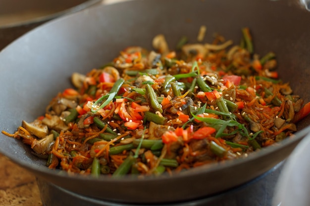 Different vegetables are cooked in a wok in a restaurant kitchen