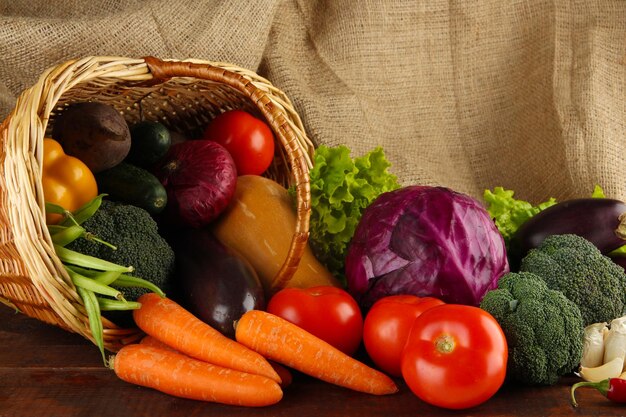 Different vegetables in basket on table on sackcloth background