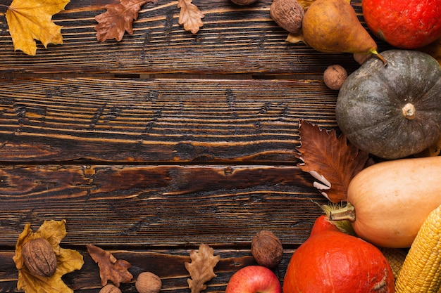 Различные овощи, тыквы, яблоки, груши, орехи, помидоры, кукуруза, сухие желтые листья на деревянном фоне. Осеннее настроение, copyspace. Уборка урожая .