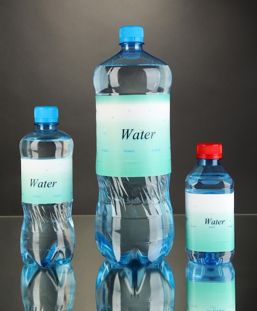 Different water bottles with label on grey background
