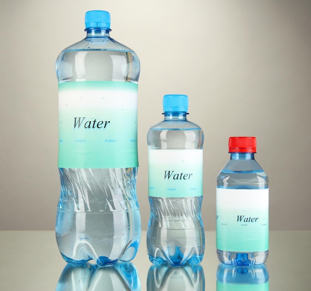 Photo different water bottles with label on grey background