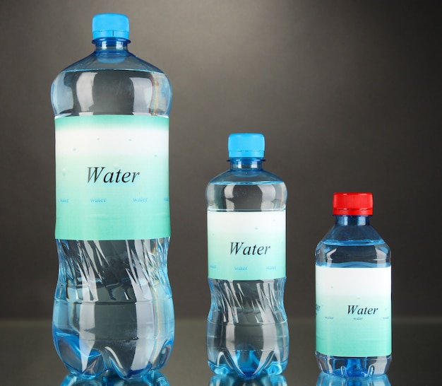 Different water bottles with label on grey wall