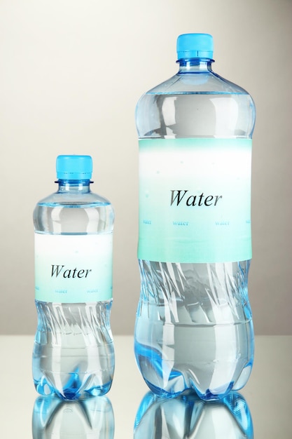 Фото Различные бутылки с водой с этикеткой на сером фоне
