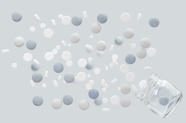 Different white and blue medical pills flying out of a glass jar