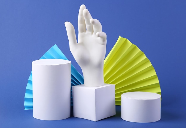 Different white geometric shapes and hand on a blue background Concept art abstract background beauty products showcase