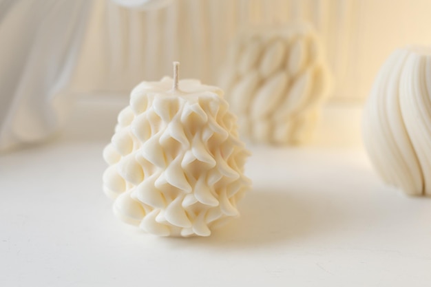 Different white wax candles stand on a table