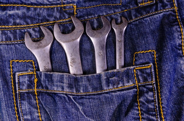 Different wrenches in a pocket of the blue jeans. Top view