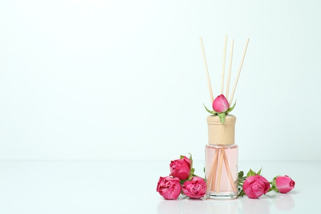 Diffuser and pink roses on white background