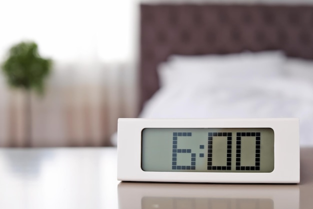 Digital alarm clock on table in bedroom Time to wake up