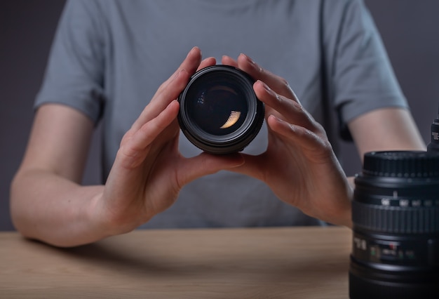 Digital camera lens 85 mm in hands of female photographer over desk.