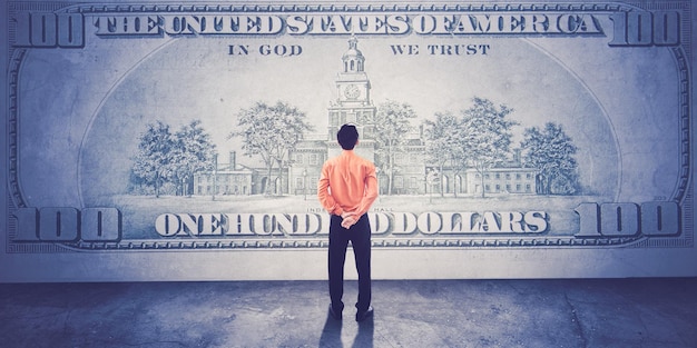 Digital composite of back view of a man in front of money one hundred dollars bill