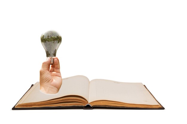 Photo digital composite of hand holding light bulb on book against white background