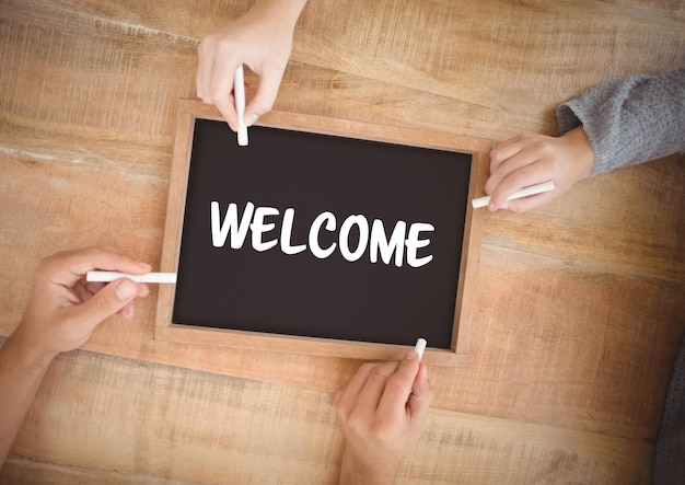 Photo digital composite of hands writing welcome text on blackboard