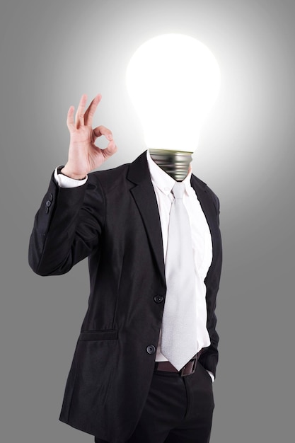 Foto immagine composita digitale di un uomo d'affari con una lampadina illuminata sullo sfondo grigio