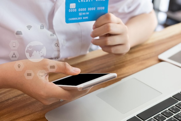 Foto immagine composita digitale di una donna d'affari con una carta di credito mentre usa il telefono sul tavolo