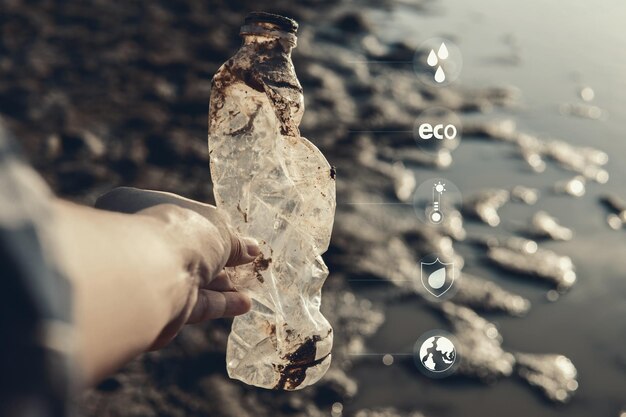 Digital composite image of cropped hand holding damaged plastic bottle