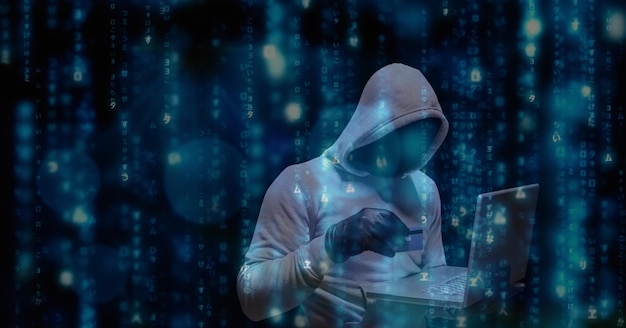 Digital composite image of hacker using credit card and laptop