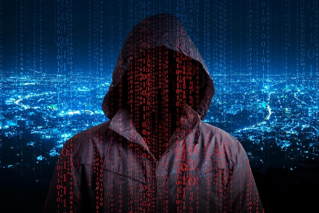 Digital composite image of hacker with binary codes against illuminated cityscape at night