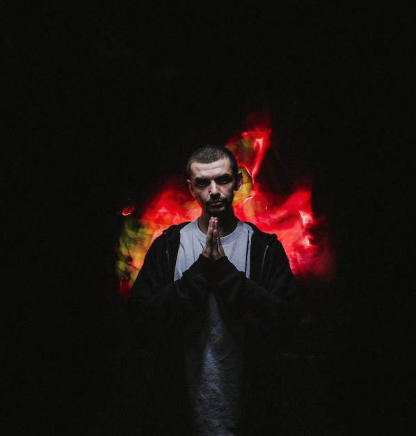 Foto immagine composita digitale di un uomo con le mani giunte in piedi in camera oscura