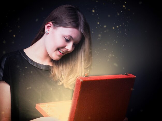 digital composite image of smiling woman opening jewelry box against black background