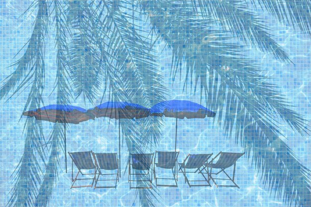 Digital composite image of swimming pool with deck chairs and parasols