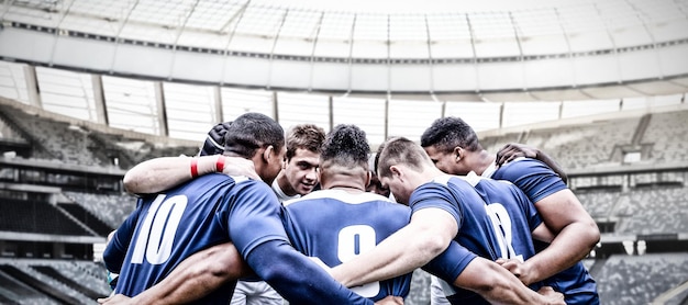 Цифровое составное изображение команды игроков в регби, стоящих в кучке на спортивном стадионе