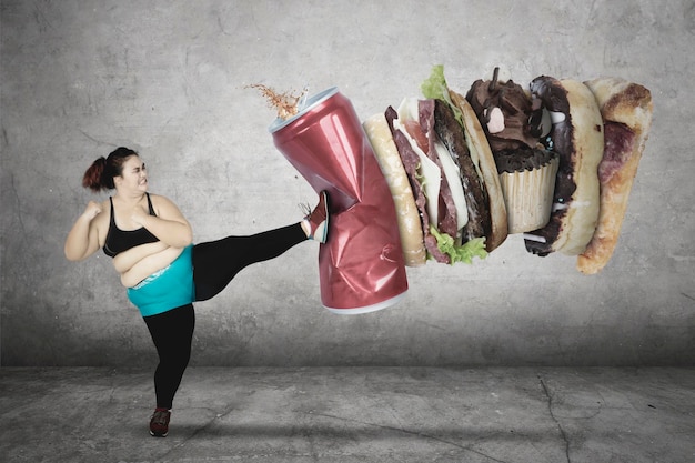 Foto immagine composita digitale di una donna che calcia il fast food contro il muro