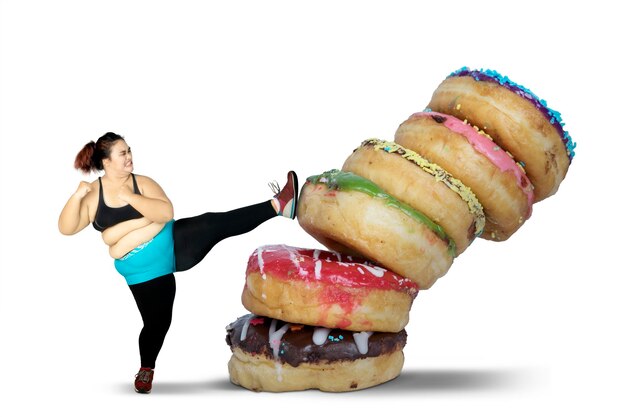 Photo digital composite image of woman kicking stacked donuts against white background