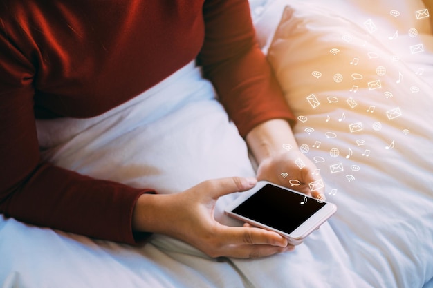 アイコン付きの携帯電話を使用している女性のデジタル複合画像