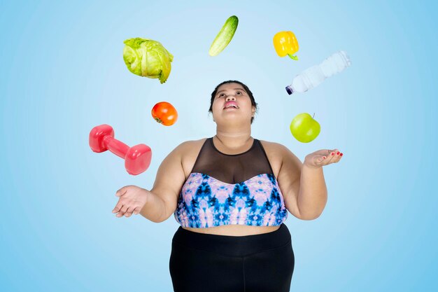 Foto immagine composita digitale di una donna con frutta e attrezzature su sfondo blu