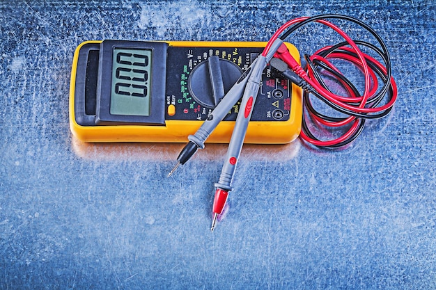 Digital electrical tester test leads on metallic background