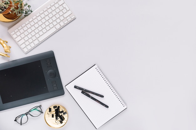 Digital graphic tablet and keyboard with stationery on white background