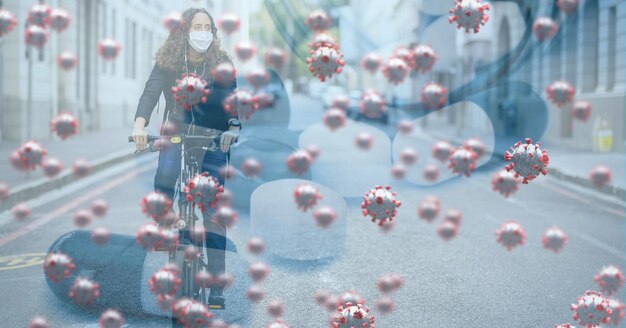 Photo digital illustration of macro covid-19 cells floating over a woman wearing a face mask, riding a bike. coronavirus covid-19 pandemic concept digitally generated