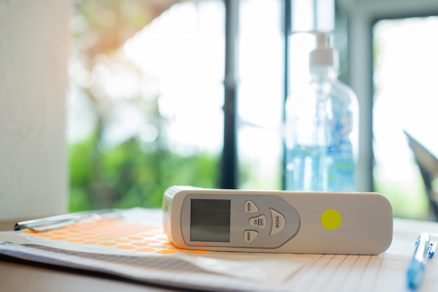 Digital Infrared thermometer and alcohol gel on the table