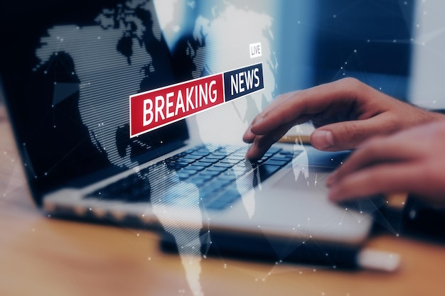 Digital and internet news concept with virtual breaking news screensaver and world map on man hands using laptop background