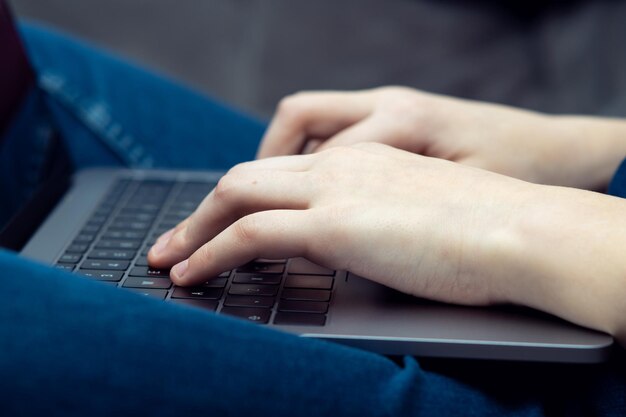 Digital laptop computer on male legs side view closeup Business man typing on keyboard of portable modern notebook