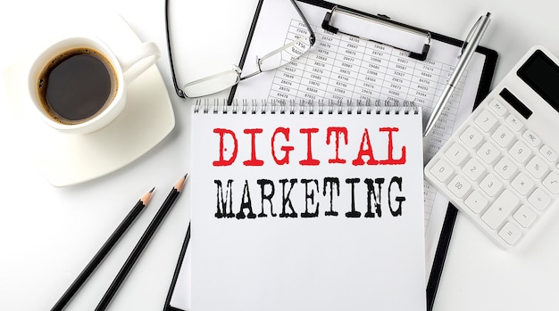 계산기, 메모장, 커피, 그래프가 있는 펜이 있는 종이의 DIGITAL MARKETING 텍스트