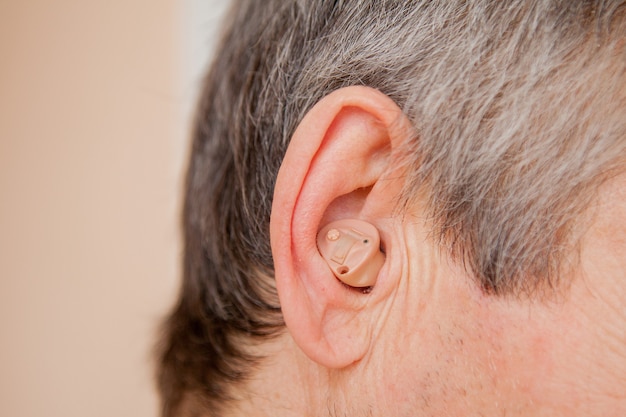 Digital modern hearing aid in the ear of an old man