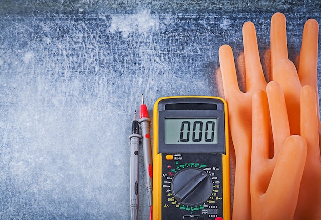 Digital multimeter dielectric rubber gloves on metallic background electricity concept