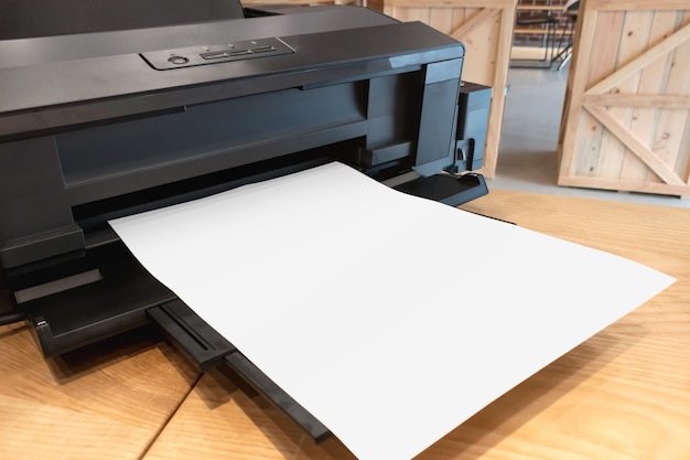 Digital paper printer and blank template on wooden table.