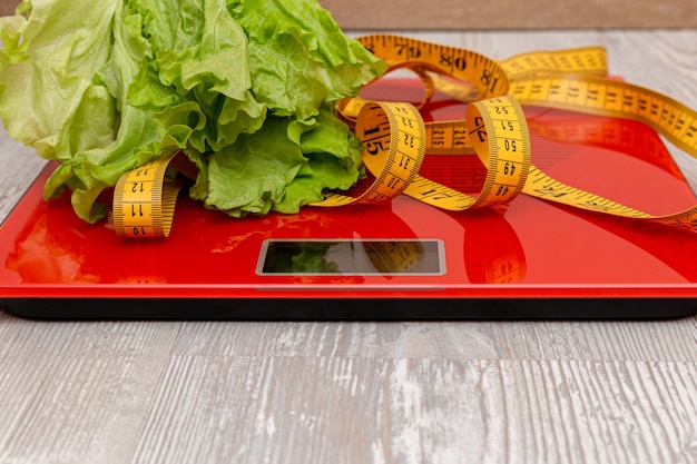 Digital scale with measuring tape and lettuce on