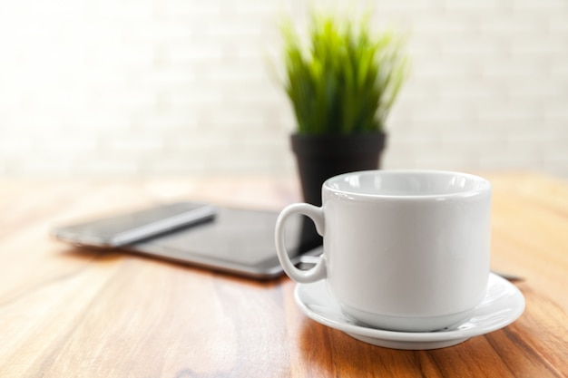 デジタルタブレットと木製のテーブルの上のブラックコーヒー
