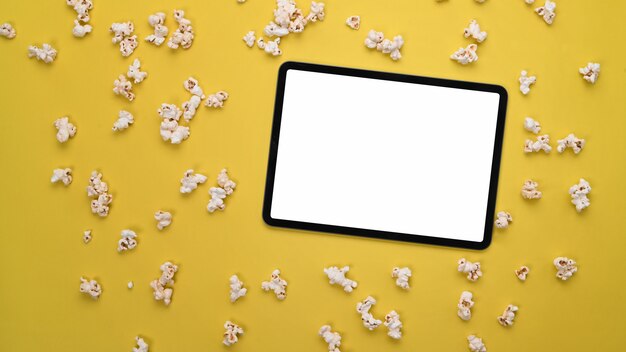 Черный экран цифрового планшета с попкорном на желтом фоне.