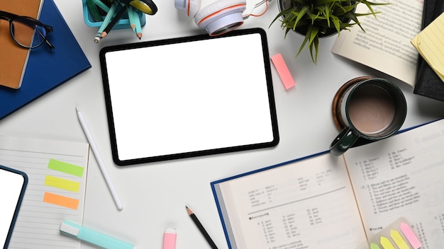 Digital tablet, book and pens on white desk