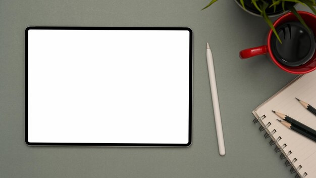 Digital tablet empty screen mockup and stylus pen on modern grey workspace background top view