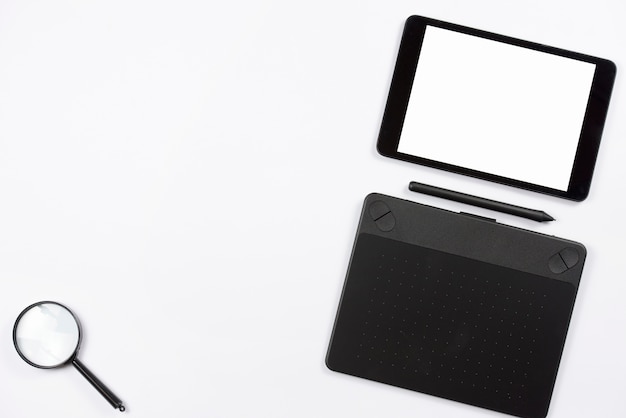 Digital tablet and graphic digital tablet with stylus and magnifying glass on white background