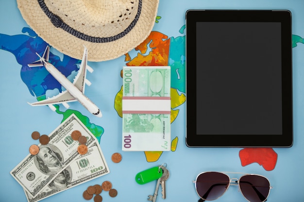 Digital tablet, hat, sunglasses, dollar and airplane model