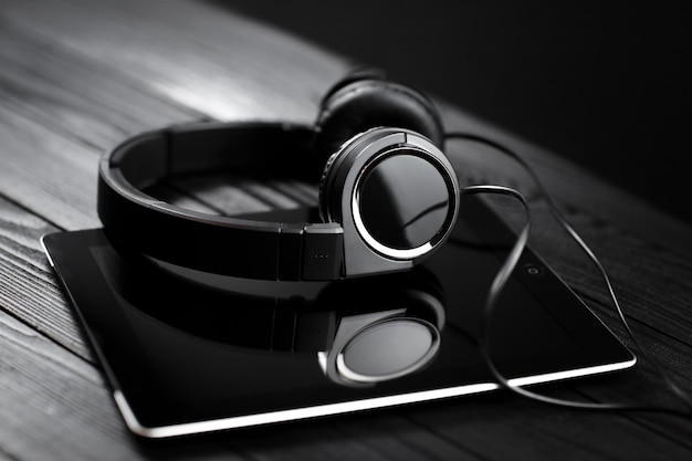 Photo digital tablet and headphones on a dark wooden table