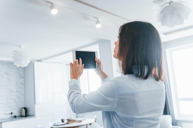 写真 手にデジタルタブレット若い女性は日中にスマートハウスの部屋で屋内にいます